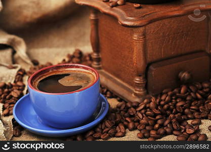 Vintage manual coffee grinder with coffee beans and cup