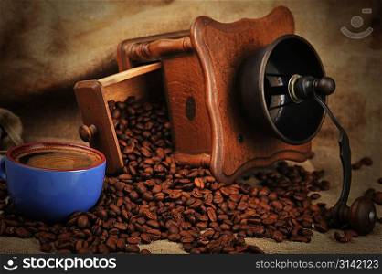 Vintage manual coffee grinder with coffee beans and cup