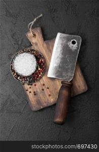Vintage meat knife hatchet on vintage chopping board and black stone table background. Butcher utensils.
