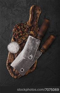 Vintage meat knife hatchets on vintage chopping board and black stone table background. Butcher.