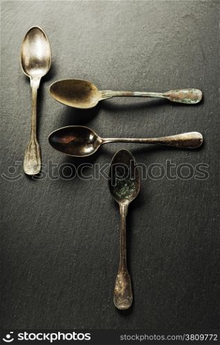 Vintage metal spoons on slate background