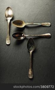 Vintage metal spoons on slate background