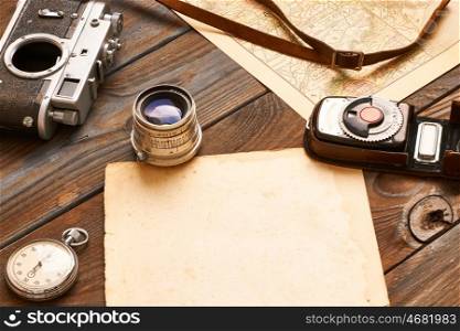 Vintage old 35mm camera, lens and light meter on wooden background with antique XIX century map