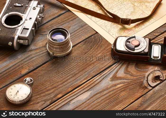 Vintage old 35mm camera, lens and light meter on wooden background with antique XIX century map