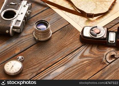 Vintage old 35mm camera, lens and light meter on wooden background with antique XIX century map