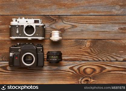 Vintage old 35mm cameras and lenses on wooden background