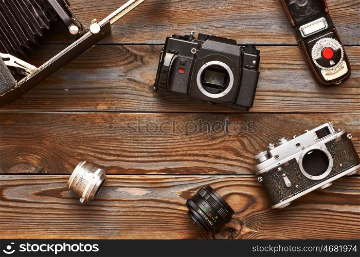 Vintage old 35mm cameras, lenses and light meter on wooden background