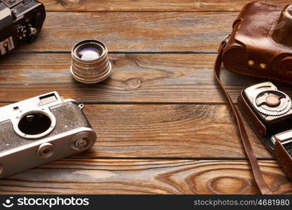 Vintage old 35mm cameras, lenses and light meter on wooden background