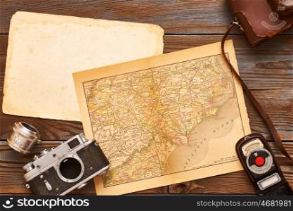 Vintage old 35mm cameras, lenses and light meter on wooden background with antique XIX century map