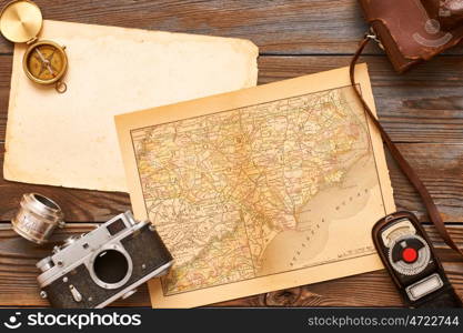 Vintage old 35mm cameras, lenses and light meter on wooden background with antique XIX century map