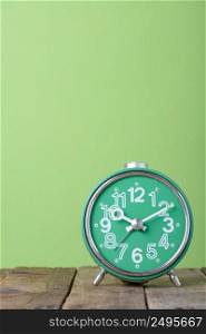 Vintage old clock on wooden table with green background and copy space