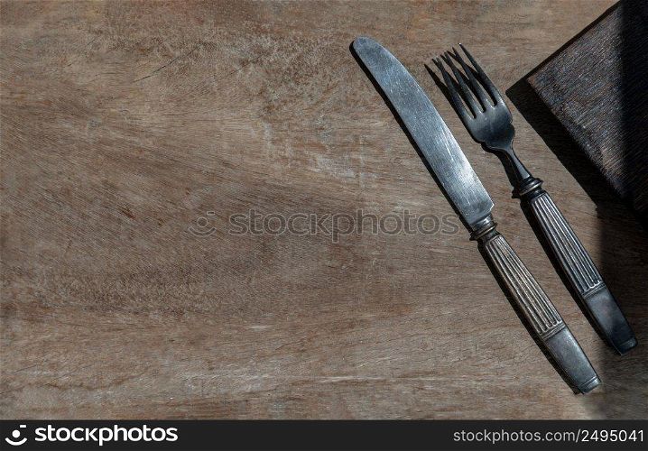 Vintage old metal knife with fork on old rustic wooden background. Eating concept, Copy space, Selective Focus.