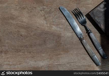 Vintage old metal knife with fork on old rustic wooden background. Eating concept, Copy space, Selective Focus.