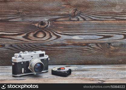 Vintage old retro 35mm rangefinder camera and light meter. Vintage old retro 35mm rangefinder camera and light meter on wooden background with copy space