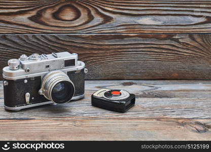 Vintage old retro 35mm rangefinder camera and light meter on wooden background with copy space