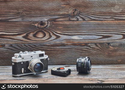 Vintage old retro 35mm rangefinder camera, lens and light meter on wooden background with copy space