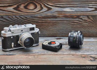 Vintage old retro 35mm rangefinder camera, lens and light meter on wooden background with copy space