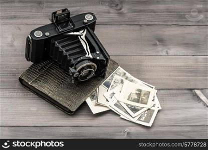 vintage photo camera and album with old photos on wooden table. memories