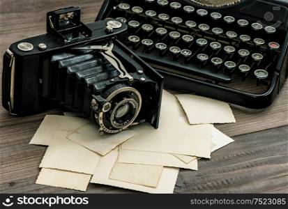 Vintage photo camera and antique typewriter on wooden background