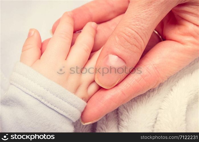 Vintage photo, Mother holding hand of her newborn baby boy, concept of babies care. Vintage photo, Hand of newborn baby in hand of mother
