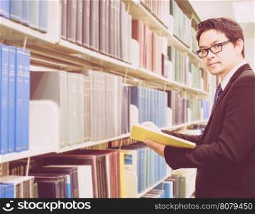 Vintage photo of businessman holding a book in a library