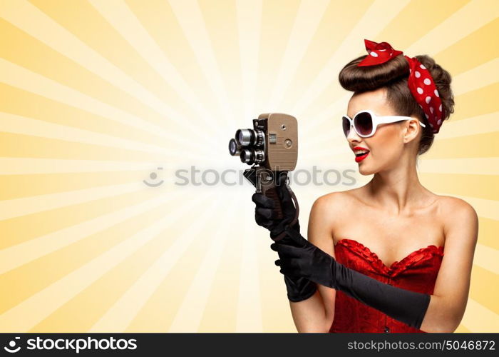 Vintage photo of glamorous pinup girl wearing a red sexy corset, filming with an old retro cinema 8 mm camera on colorful abstract cartoon style background.