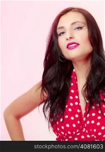 Vintage pinup style. Portrait of beautiful stylized young woman. Attractive brunette girl in retro spotted red dress on pink. Disguise. Studio shot.