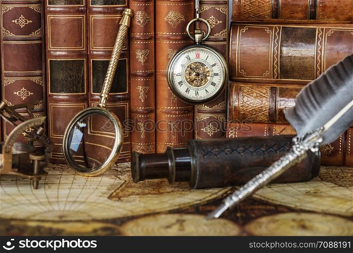 Vintage pocket watch, navigation instruments and silver pen are on the background of antique books