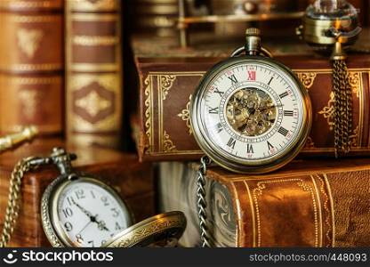 Vintage pocket watch on the background of antique books. Allegory of time