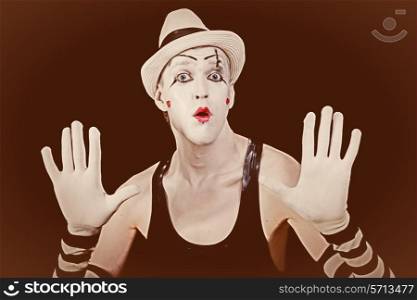 Vintage portrait of a circus clown in a white hat on a black background