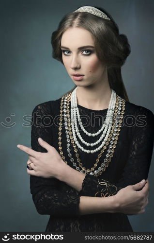 vintage portrait of beautiful brunette woman posing like a antique dame with precious crown and necklaces, retro hair-style