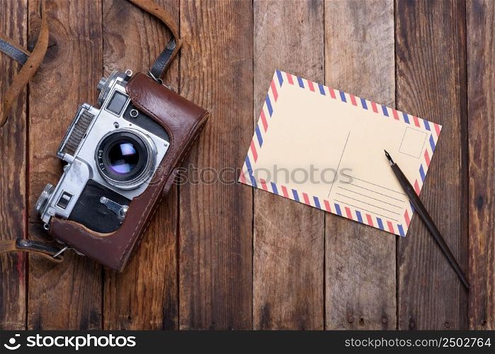 Vintage post card and retro camera on old wooden table