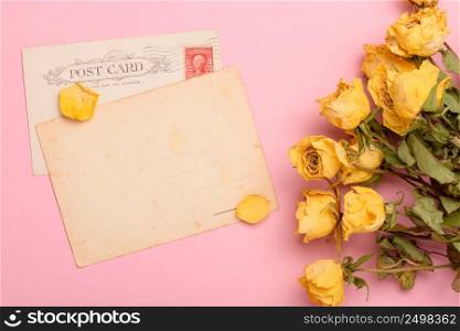 Vintage post cards with dry yellow roses flowers on pastel rose background top view