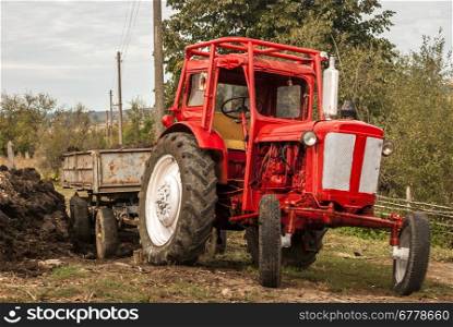 Vintage red grunge tractor on rural landscape