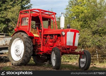 Vintage red grunge tractor on rural landscape