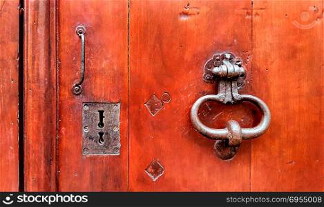 Vintage red wooden door with metallic doorhandle and keyholes, Troyes, France