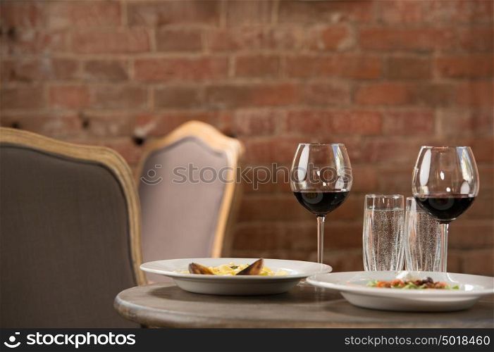 Vintage restaurant interior. Closeup of table with two meals and wine glasses. Prepared for two
