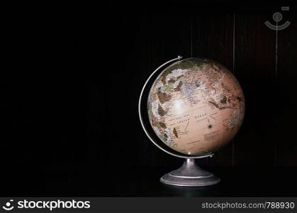 Vintage retro classic school globe model of Earth. Icon of globe. Sphere map of continents and oceans on world model on black dark back ground
