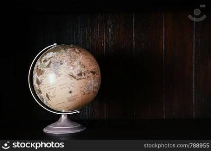 Vintage retro classic school globe model of Earth. Icon of globe. Sphere map of continents and oceans on world model on dark wooden back ground