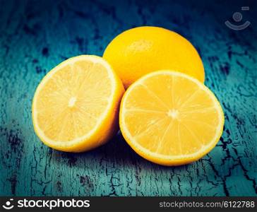 Vintage retro effect filtered hipster style image of lemon and cut half slice on blue wooden background. Lemon and cut half slices