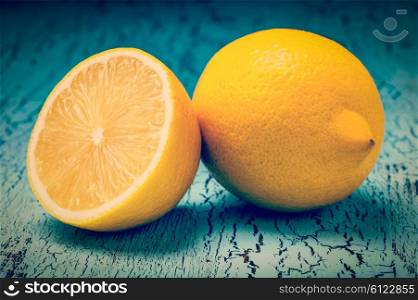 Vintage retro effect filtered hipster style image of lemon and cut half slice on blue wooden background. Lemon and cut half slice