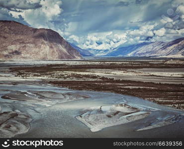 Vintage retro effect filtered hipster style image of Nubra valley and Nubra river in Himalayas. Ladakh, Jammu and Kashmir, India. Nubra valley and river in Himalayas, Ladakh