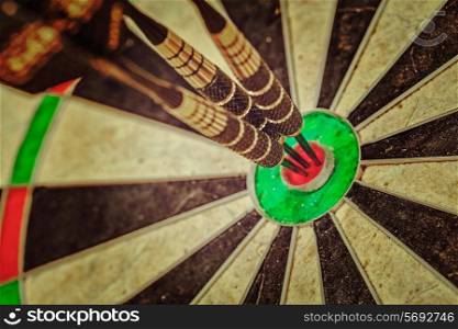 Vintage retro effect filtered hipster style image of - Success hitting target aim goal achievement concept background - three darts in bull&#39;s eye close up