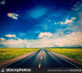 Vintage retro effect filtered hipster style image of travel concept background - road in blooming spring meadow