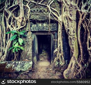Vintage retro effect filtered hipster style travel image of ancient stone door and tree roots, Ta Prohm temple ruins, Angkor, Cambodia