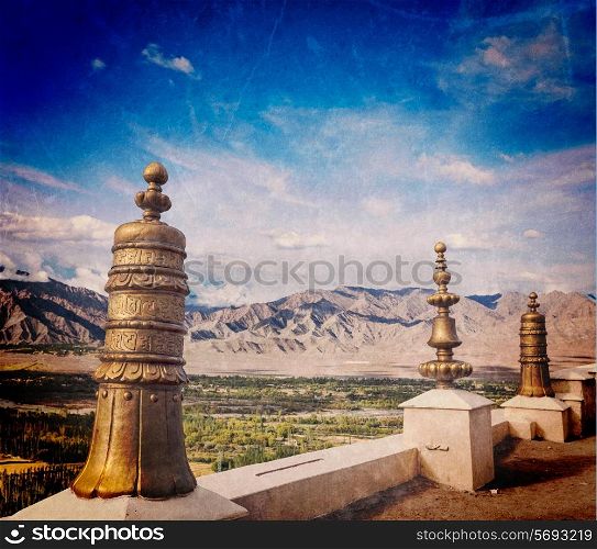 Vintage retro effect filtered hipster style travel image of Dhvaja victory banners, on the roof of Thiksey gompa monastery and view of Indus valley with grunge texture overlaid. Ladakh, India