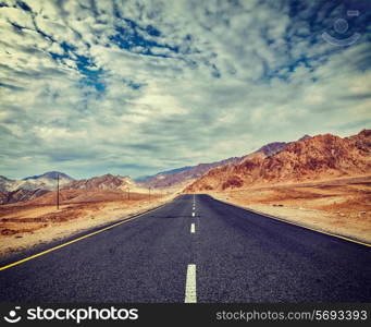 Vintage retro effect filtered hipster style travel image of Travel forward concept background - road in Himalayas with mountains and dramatic clouds. Ladakh, Jammu and Kashmir, India