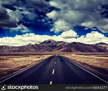 Vintage retro effect hipster style image of Travel forward concept background - road on plains in Himalayas with mountains and dramatic clouds. Manali-Leh road, Ladakh, Jammu and Kashmir, India