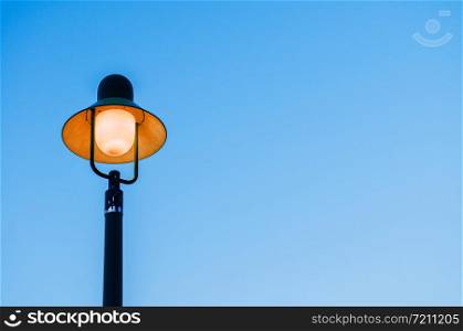 Vintage retro electric light pole with blue evening sky background with copy space on one side for design work