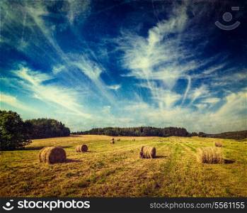 Vintage retro hipster style travel image of Agriculture background - Hay bales on field in summer with grunge texture overlaid